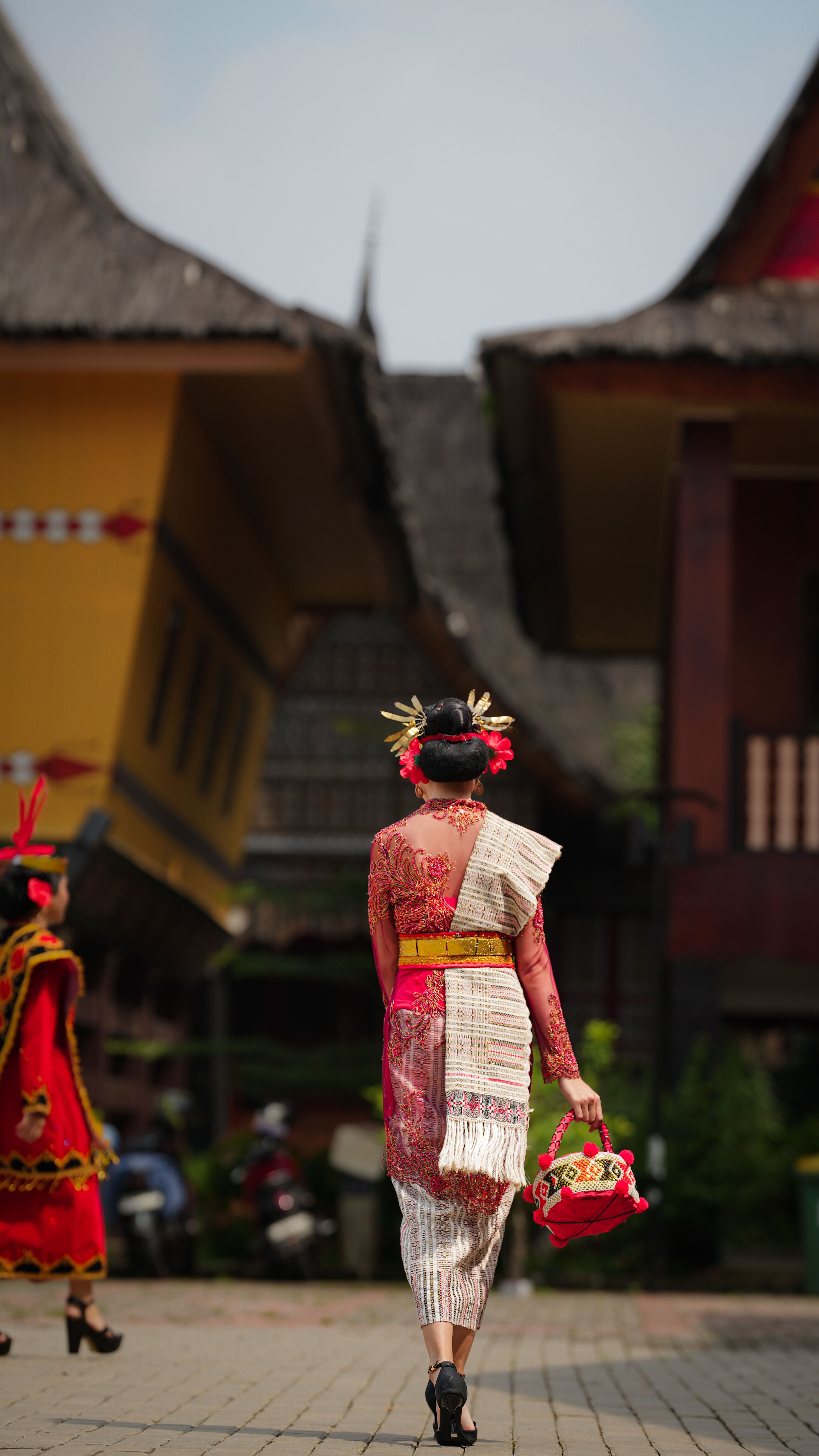 Back view of a woman in traditional attire walking in Jakarta, Indonesia.