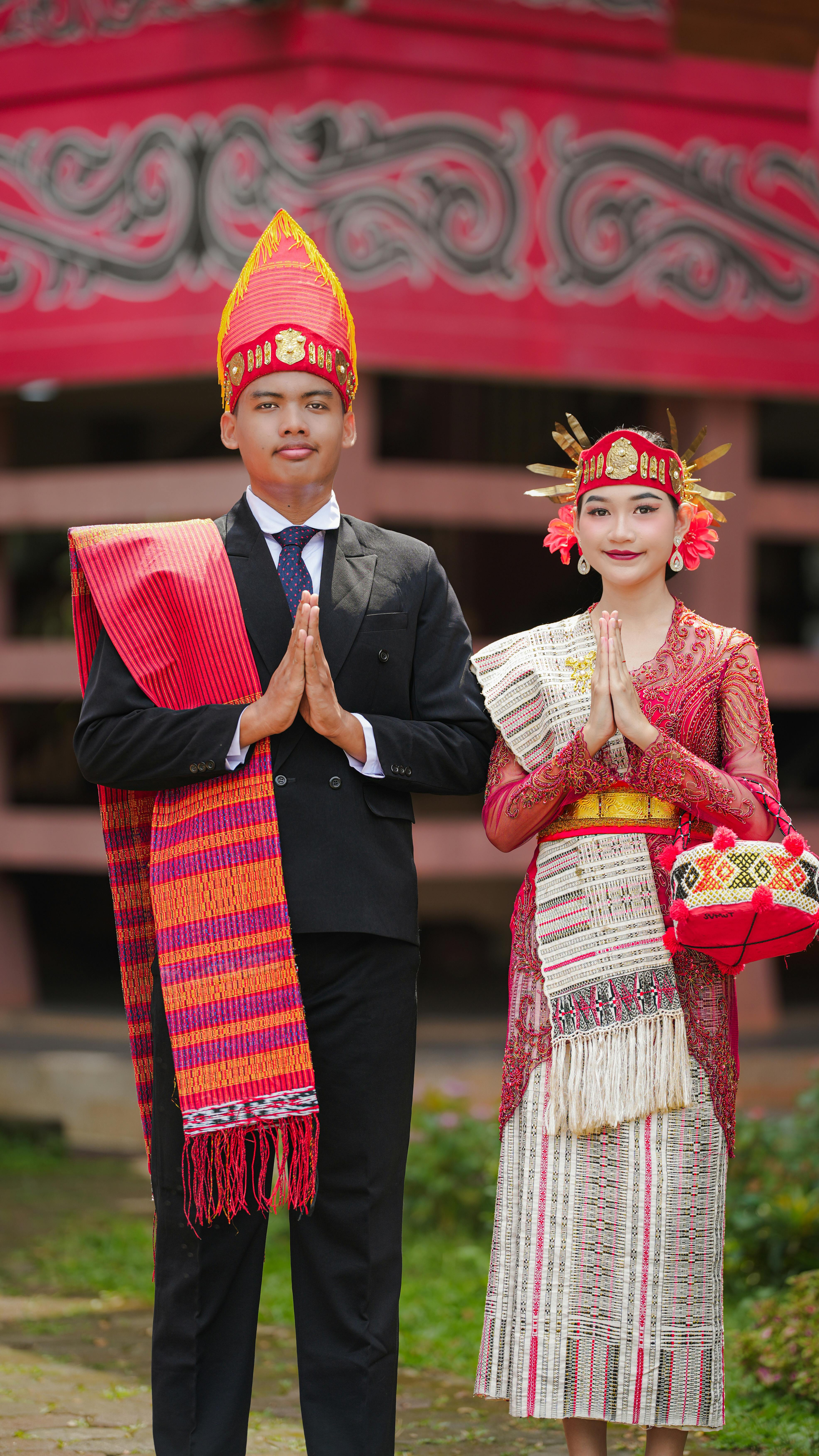 A man and woman in traditional Indonesian attire pose during a cultural ceremony in Jakarta.