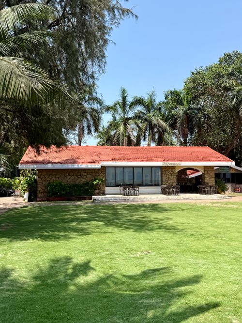 Free Cozy bungalow with a red roof surrounded by palm trees and green lawn. Stock Photo