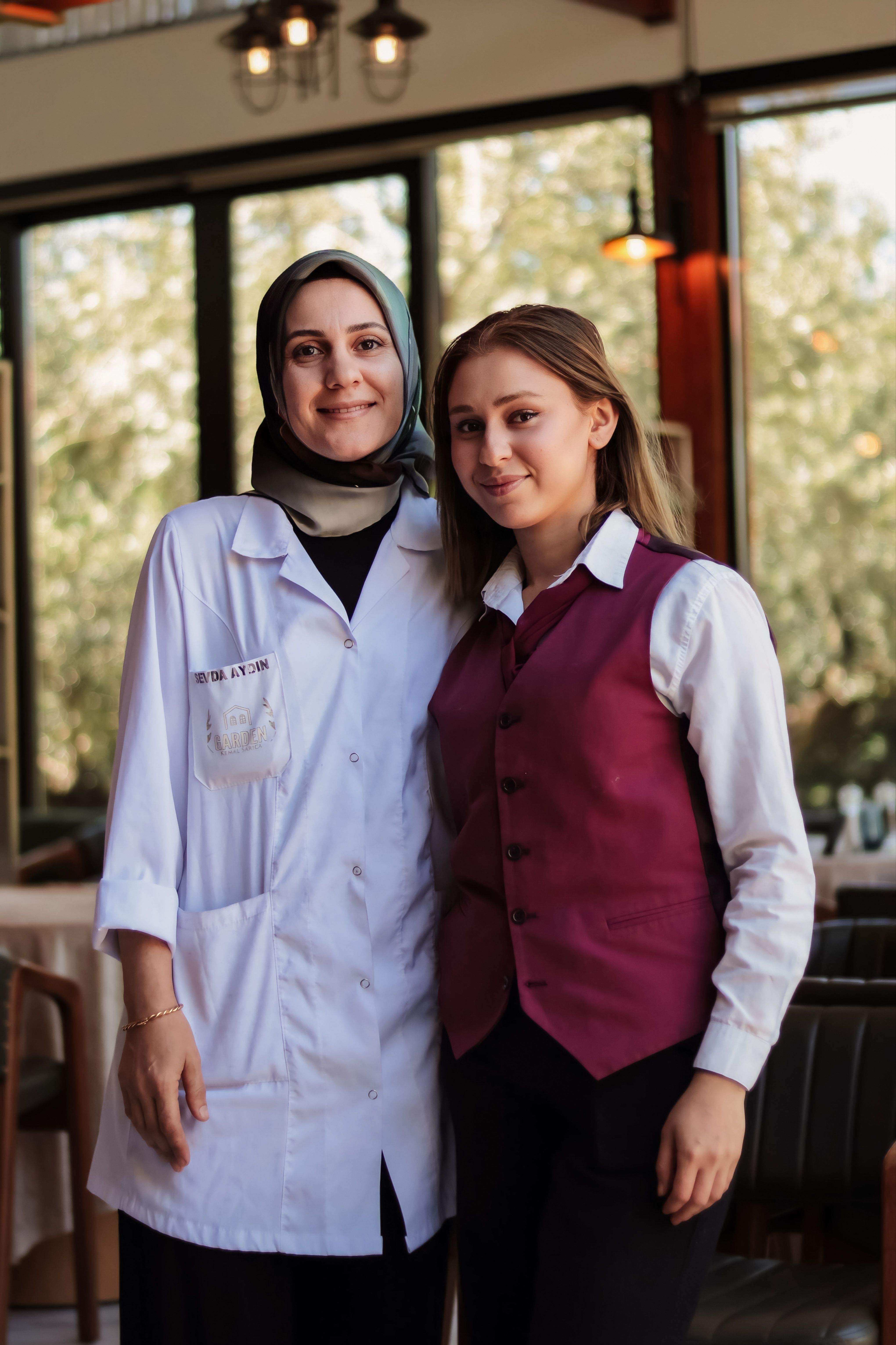 Two women, a doctor and a waitress, smiling in a restaurant setting.