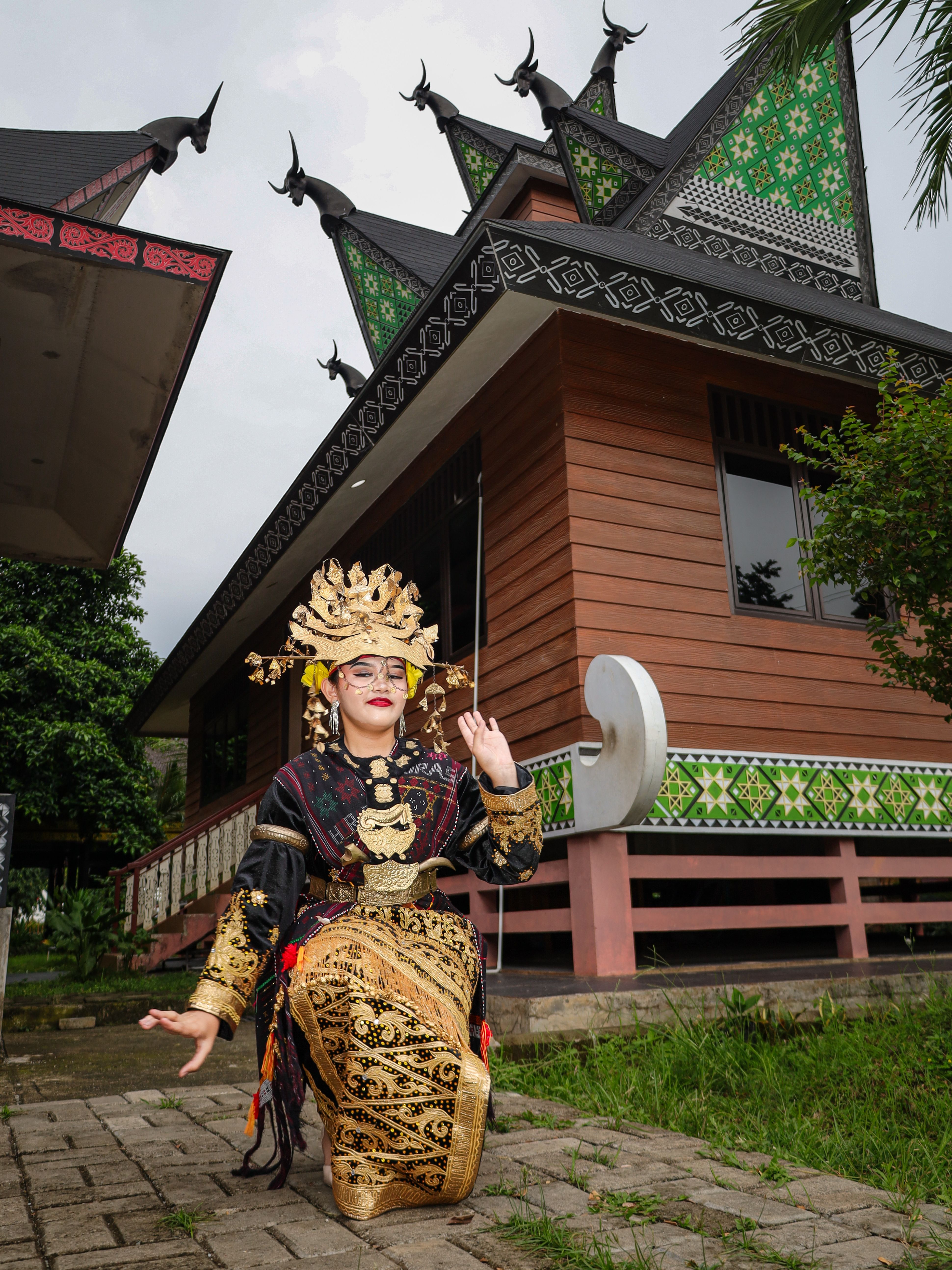 A traditional dancer poses in front of Jakarta's cultural architecture showcasing intricate design and vibrant attire.