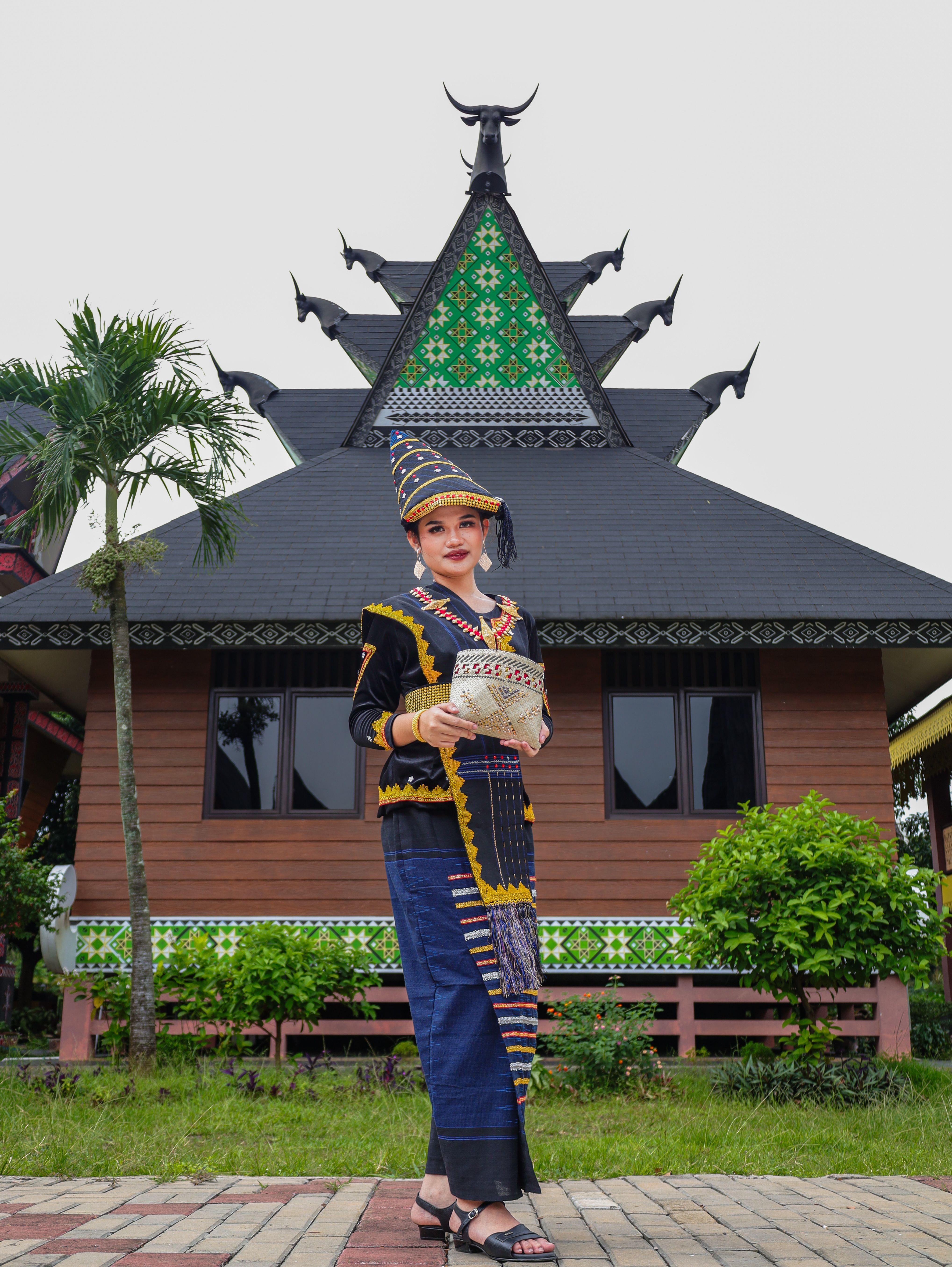 Gratuit Une femme en tenue traditionnelle pose devant la façade d'un bâtiment culturel. Photos