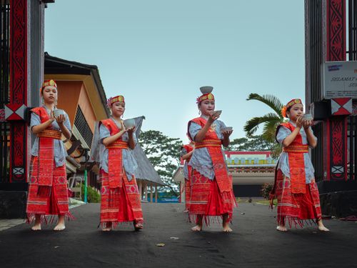 Free Four young dancers in vibrant traditional attire performing a cultural dance outdoors. Stock Photo