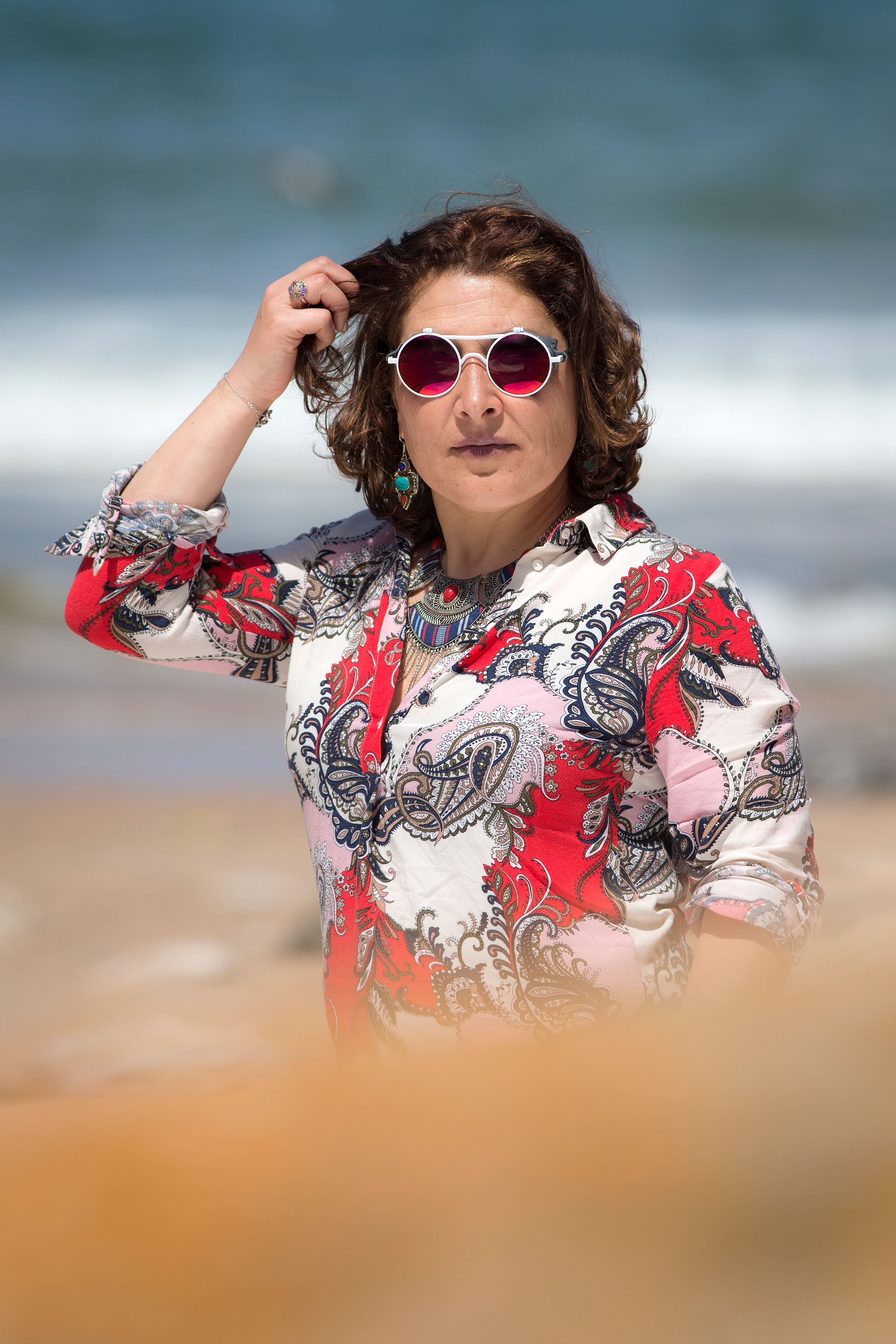Stylish woman with sunglasses enjoying a sunny day at the beach in summer.
