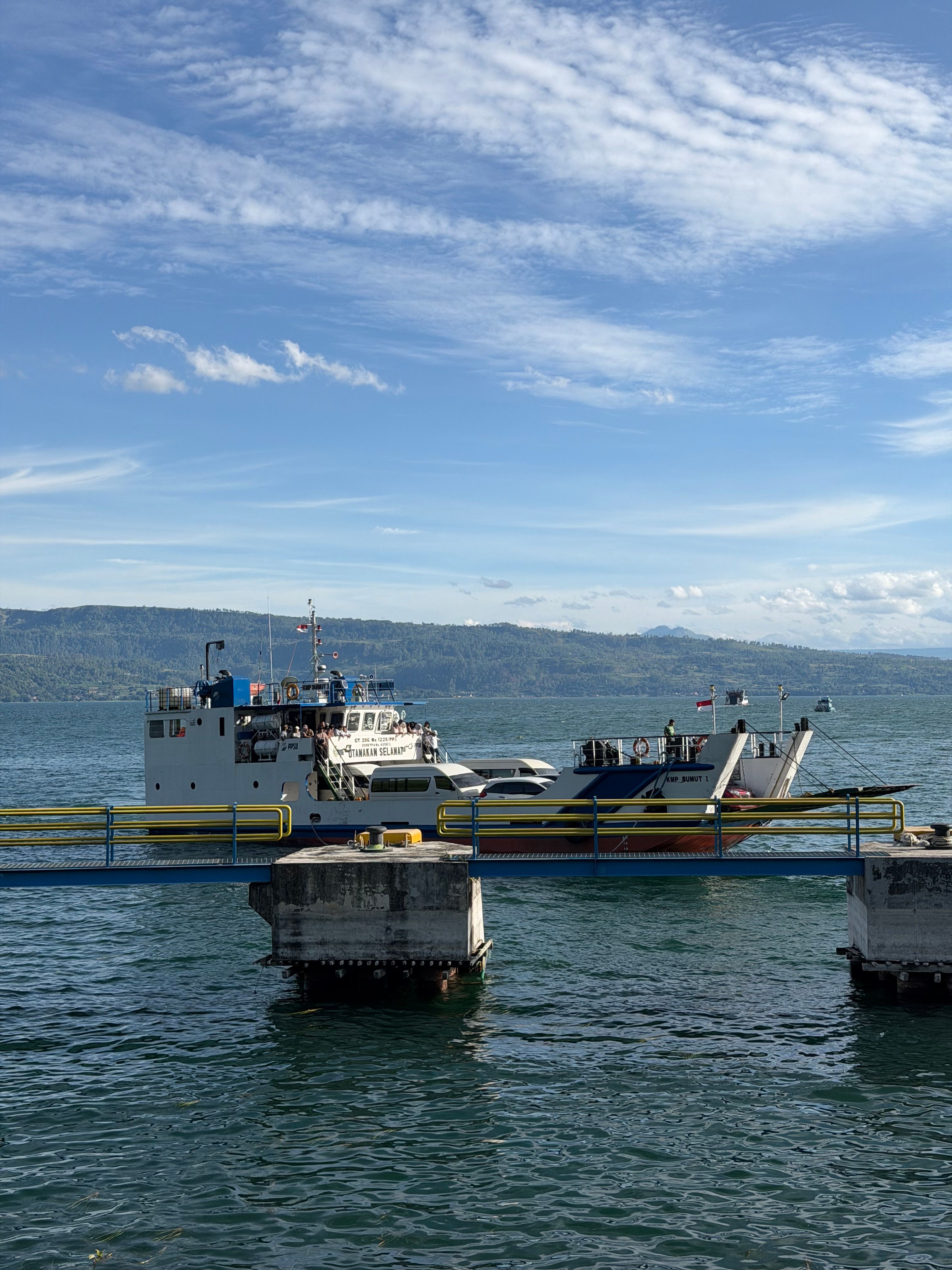 Ferry boat docked at Lake Toba with scenic mountain views. Ideal for travel enthusiasts.