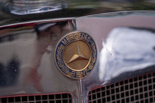 Detailed view of a classic car's metal grille featuring a prominent golden emblem.