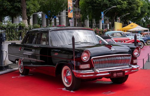 Free Vintage black car showcased on red carpet at outdoor auto event. Stock Photo