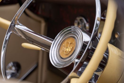 Detailed view of a classic car steering wheel featuring a vintage emblem.