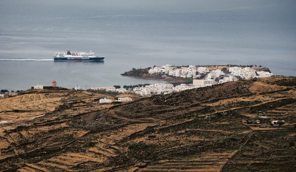 Ferry boat cruising the Aegean Sea near a picturesque Greek island village.