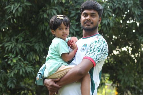 Free A father lovingly holds his child in a green leafy outdoor setting during summer. Stock Photo