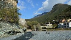 Discover the stunning landscape of Olmeta-di-Capocorso, featuring rustic architecture and scenic mountains.