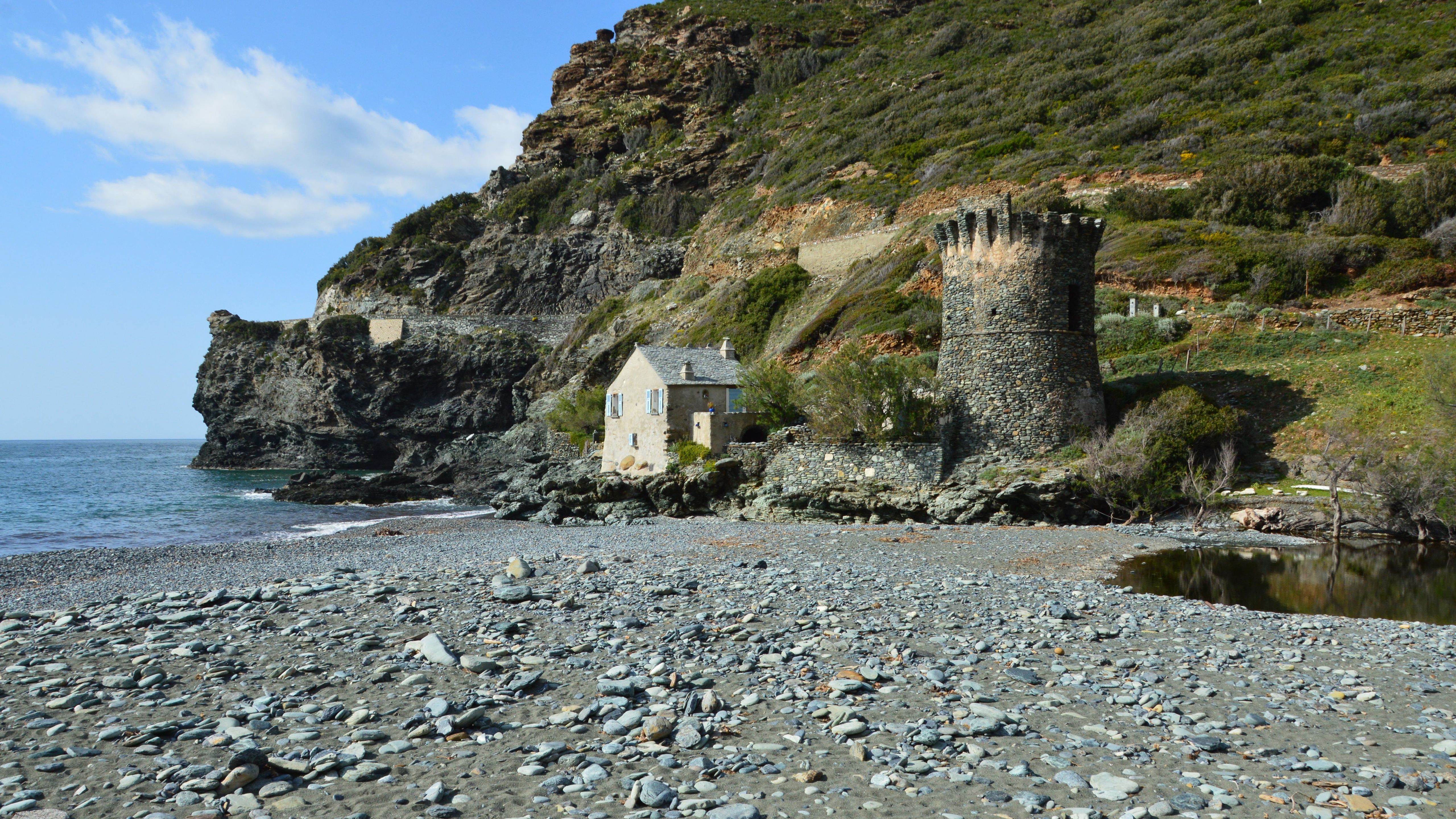 Stone tower and house by the rocky beach at Olmeta-di-Capocorso, Corse, France.
