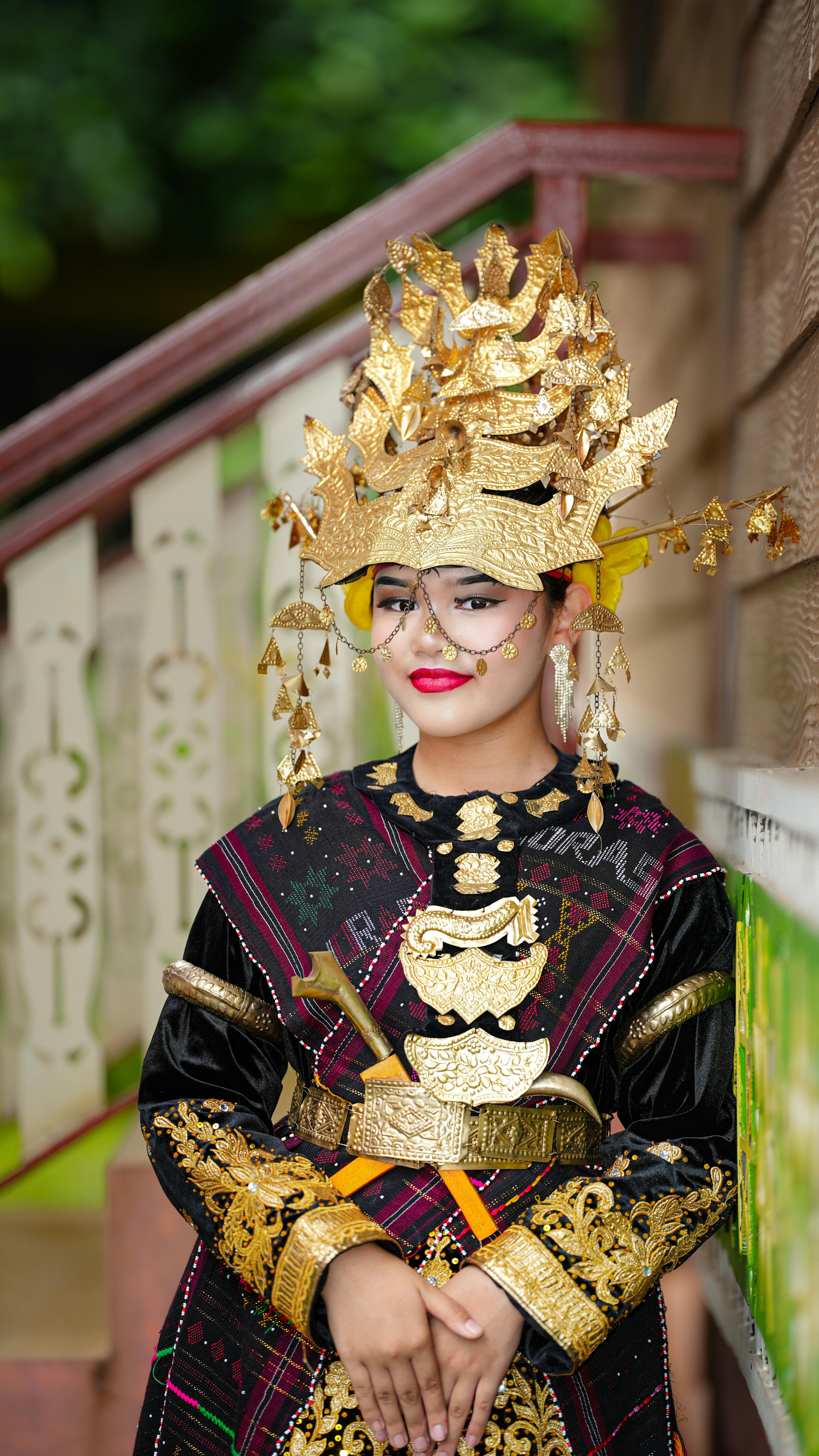 A woman in traditional Minangkabau attire with intricate gold headpiece, Indonesia.