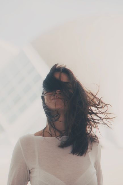 Fotomural Una mujer se encuentra con el pelo soplando al viento, capturando un momento de libertad y espontaneidad al aire libre.