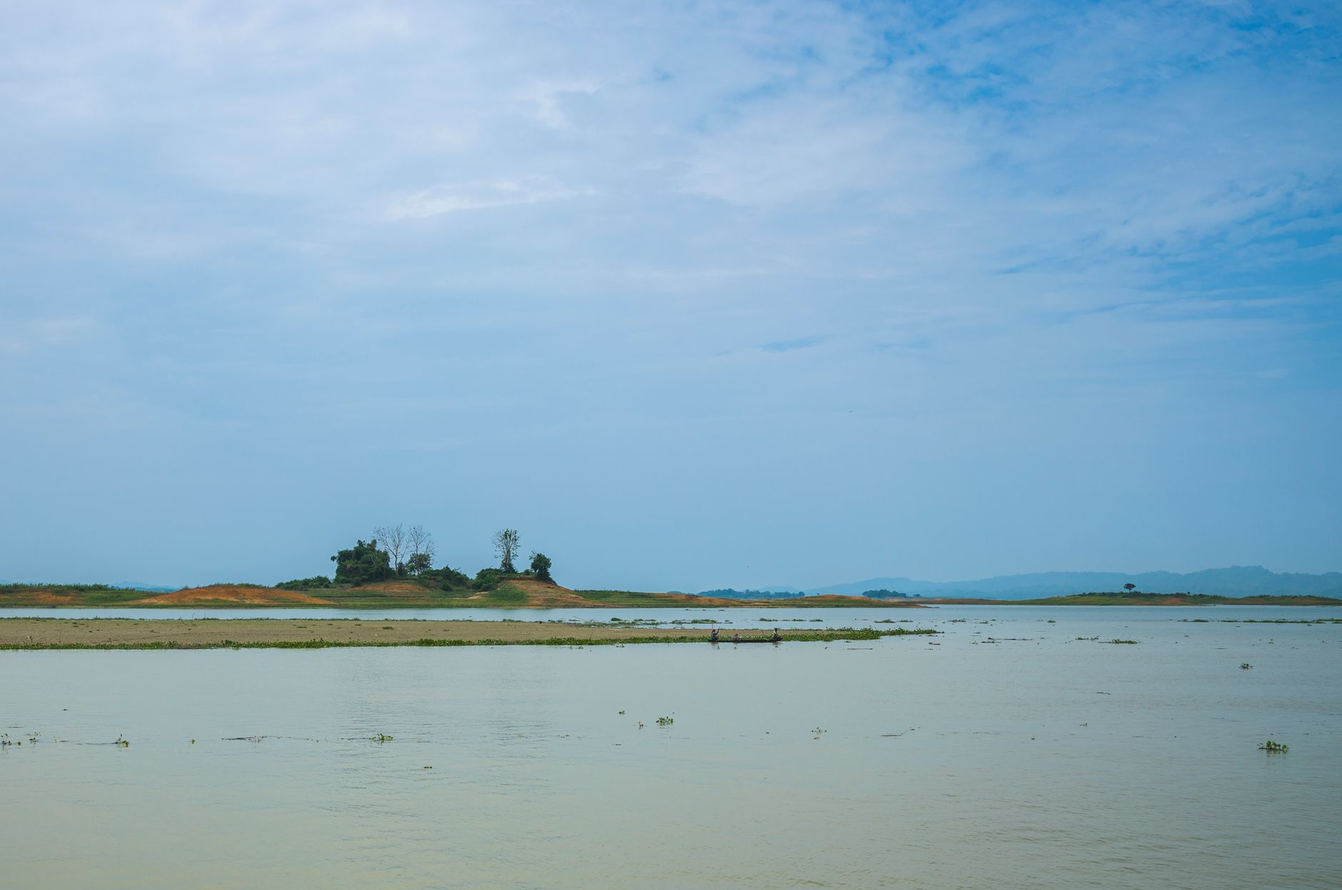 Tranquil view of a lake with an island under a blue sky, perfect for nature lovers.