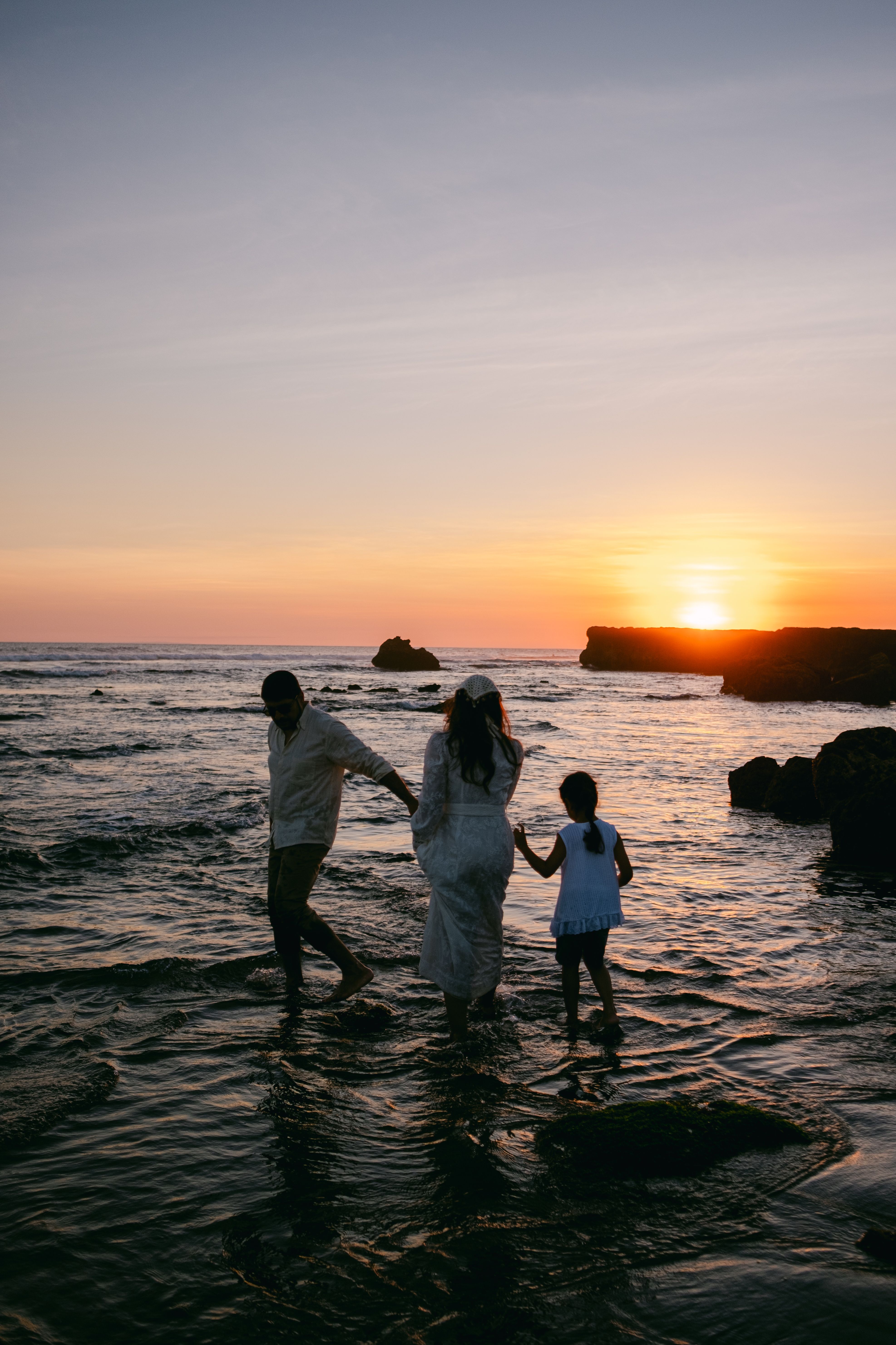 A family strolls along the beach at sunset, enjoying the serene seaside atmosphere.