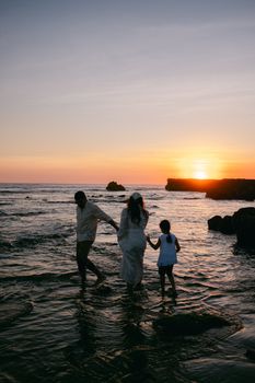 A family strolls along the beach at sunset, enjoying the serene seaside atmosphere.