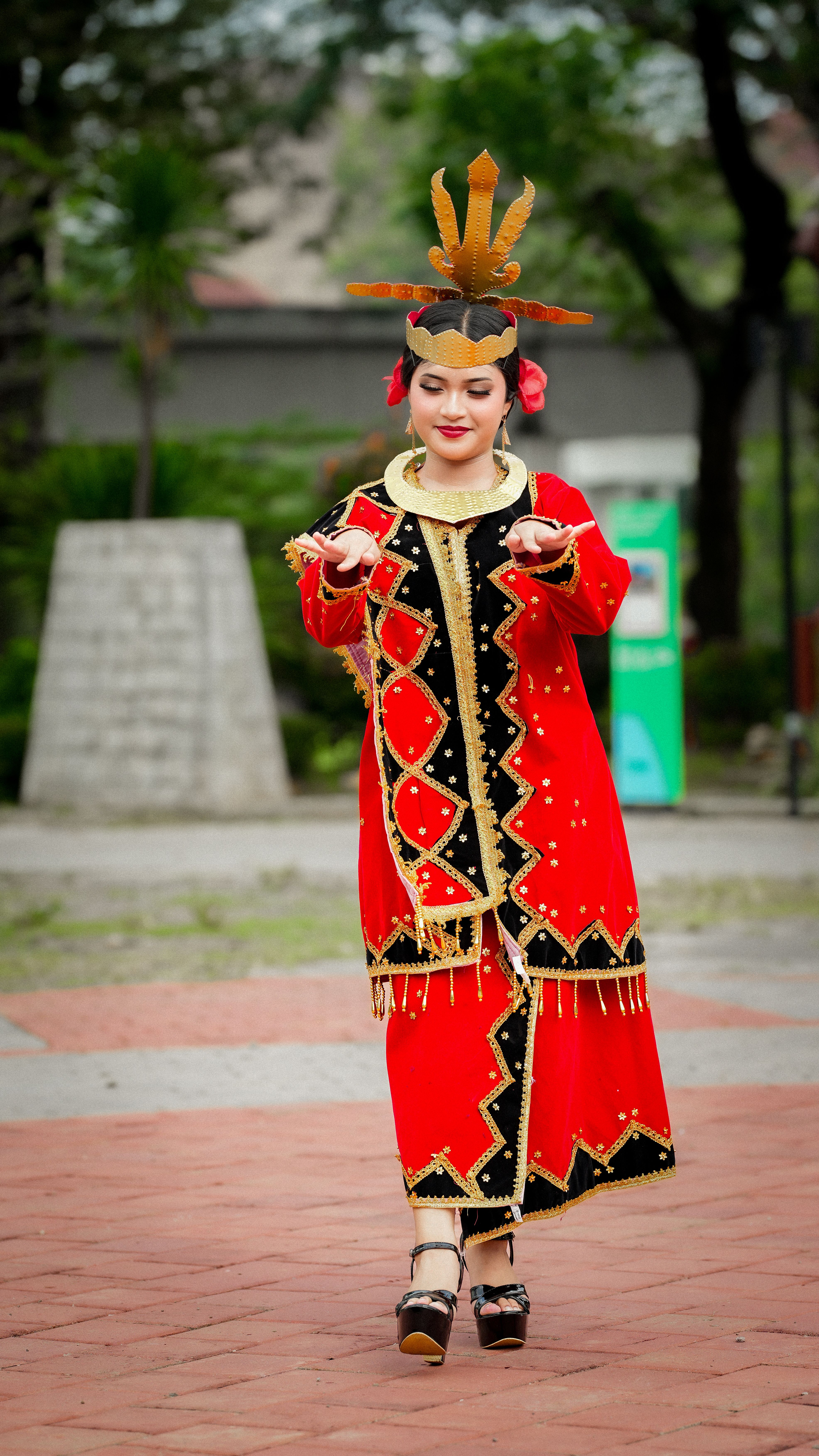 Woman performing traditional Indonesian dance in colorful attire outdoors.