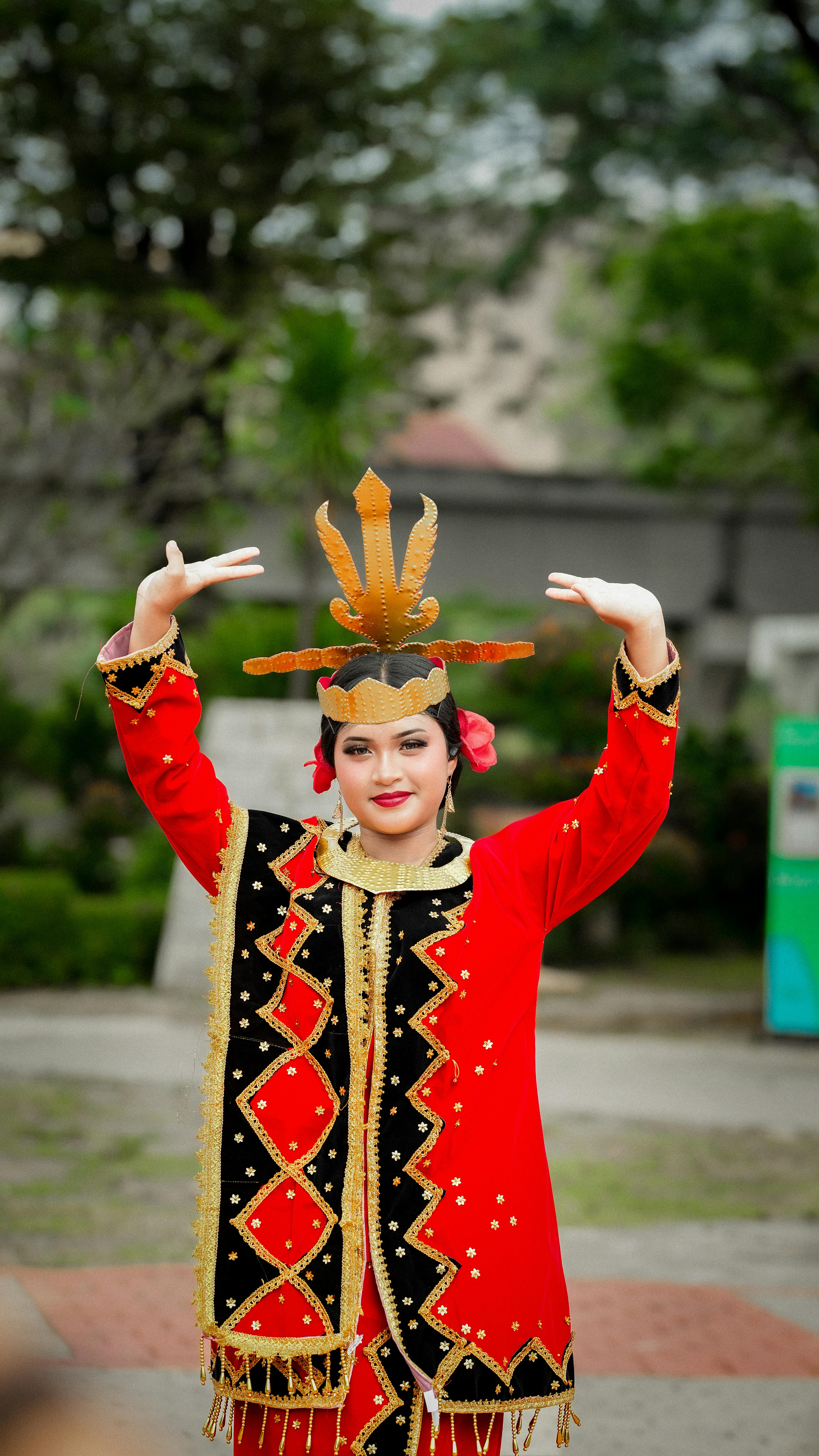 Young woman performing in traditional Indonesian costume in a park.