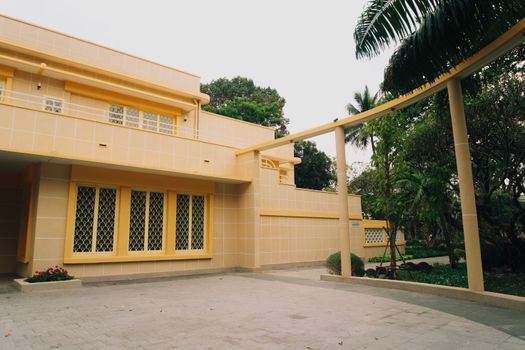 Stylish yellow house with garden, palm trees, and open driveway. - Fotografer Sidoarjo