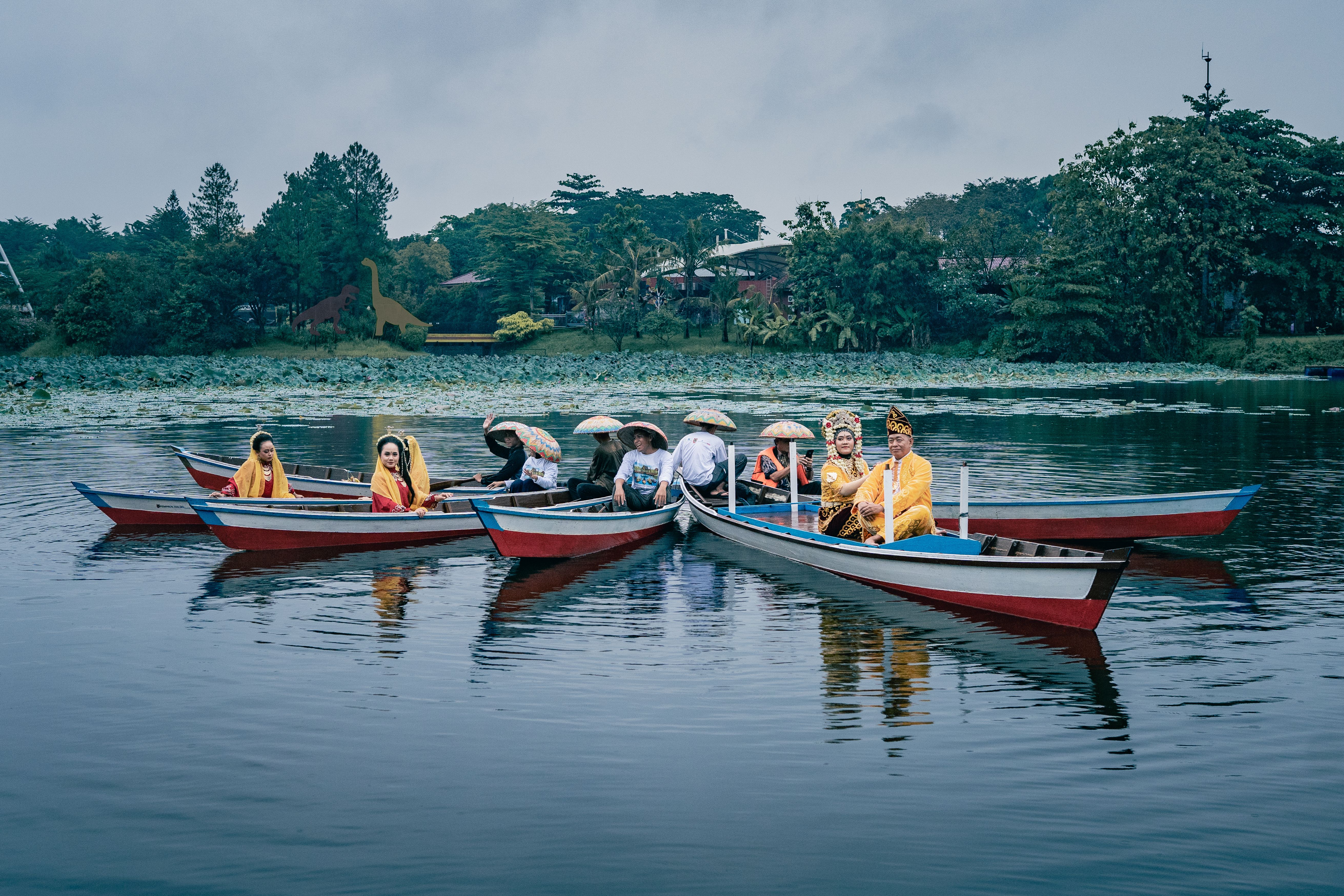 Vibrant display of Indonesian culture with people in traditional dress on colorful boats in Kalimantan Selatan.