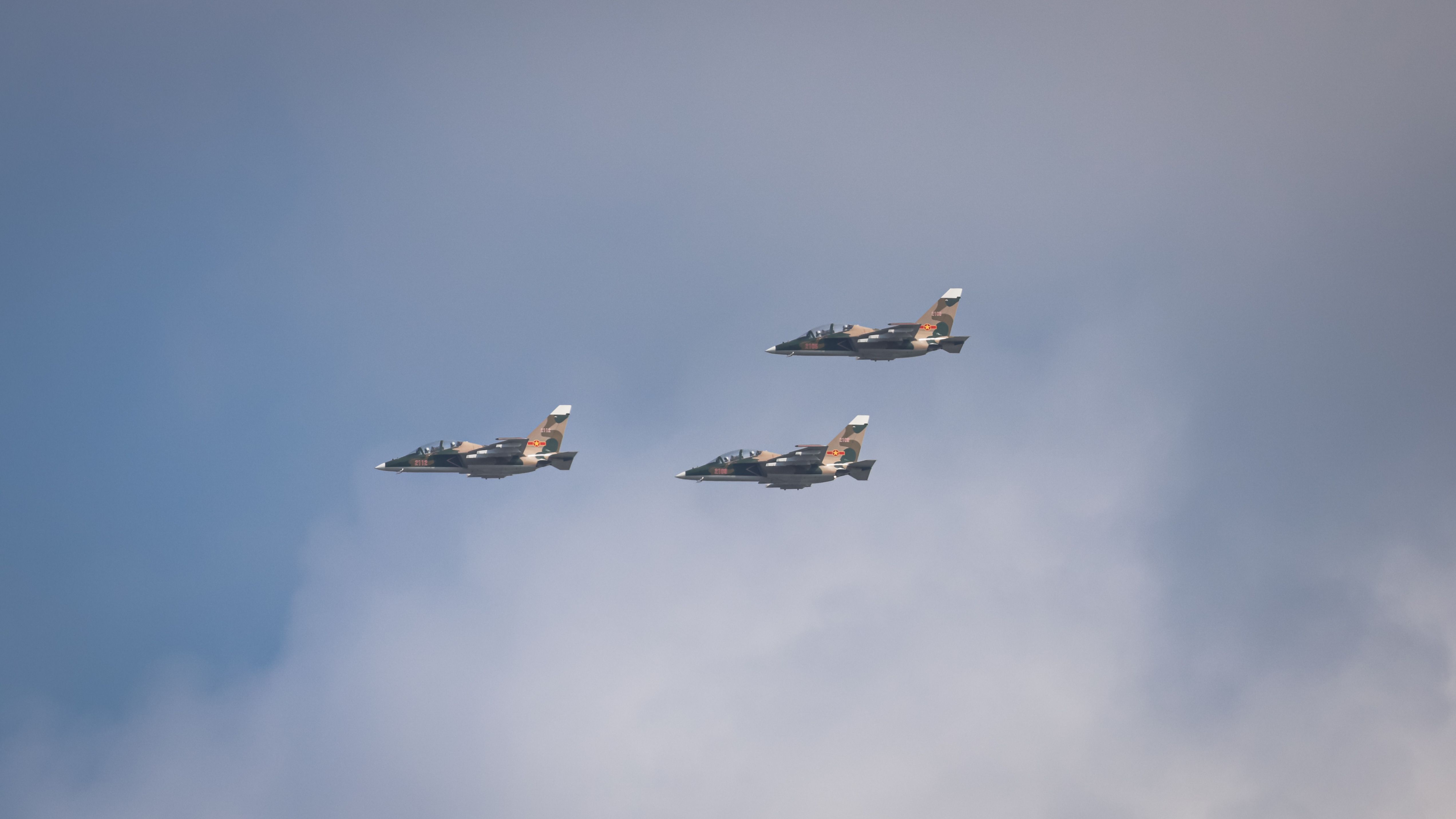 Three fighter jets flying in formation against a clear blue sky.