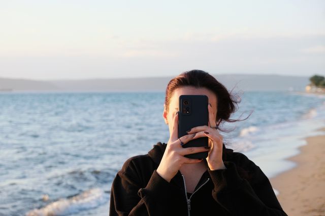 Photographer framing a coastline on a phone, photo by Renkgezgini on Pexels