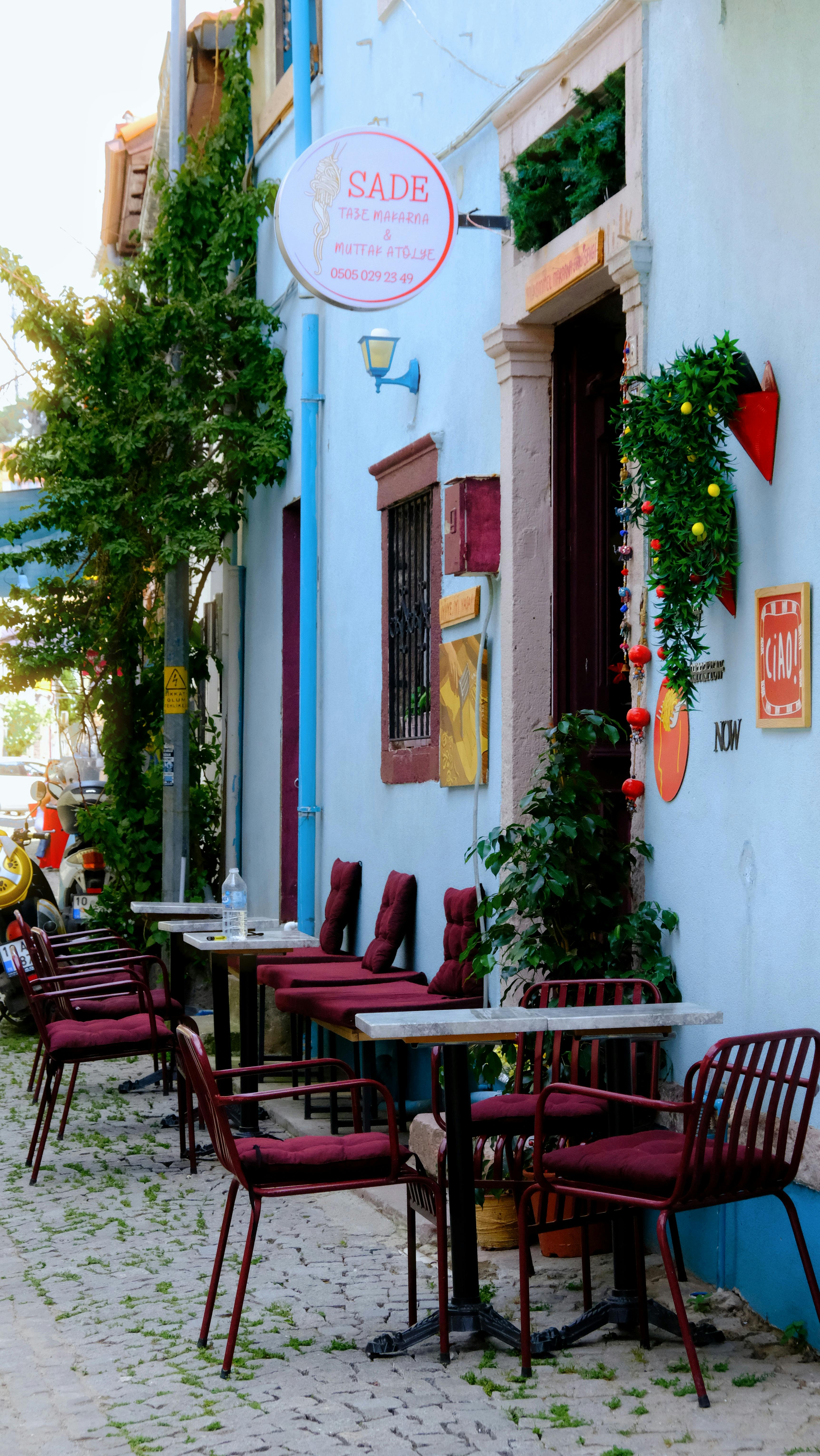 Charming cafe scene with red chairs and colorful walls on a cobblestone street, perfect for a pleasant day out.