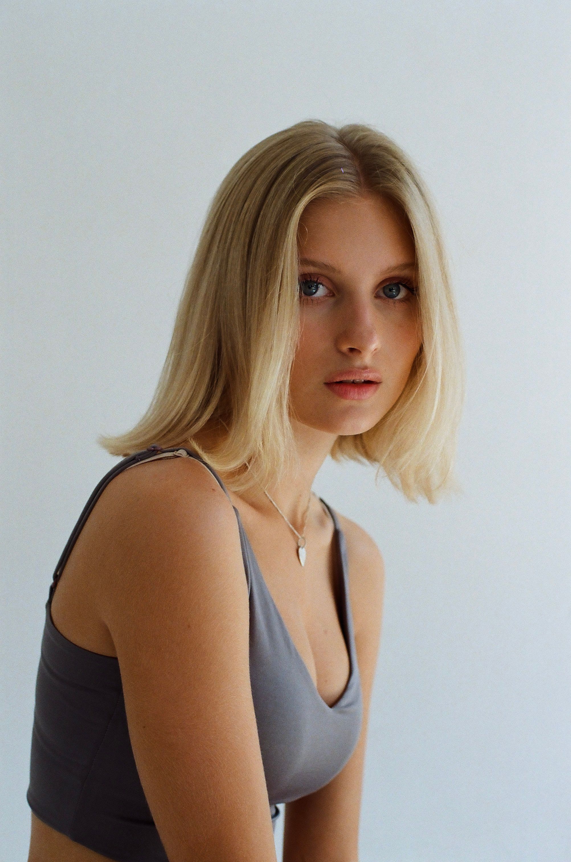Young blonde woman in a minimalist studio setting, looking thoughtful.