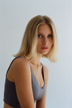 Young blonde woman in a minimalist studio setting, looking thoughtful.