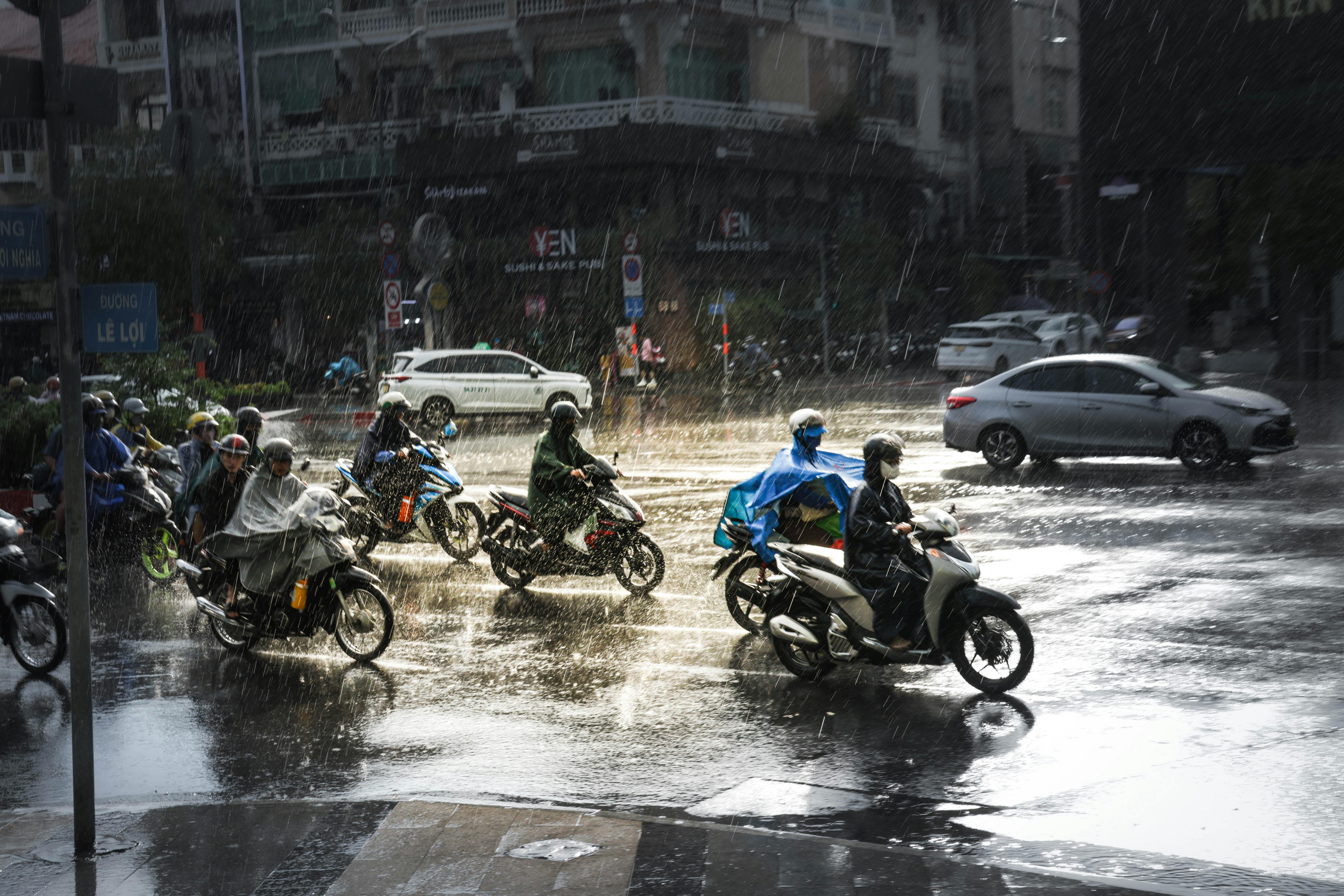 Motorcyclists navigate a rainy intersection in Ho Chi Minh City, showcasing urban resilience and mobility.