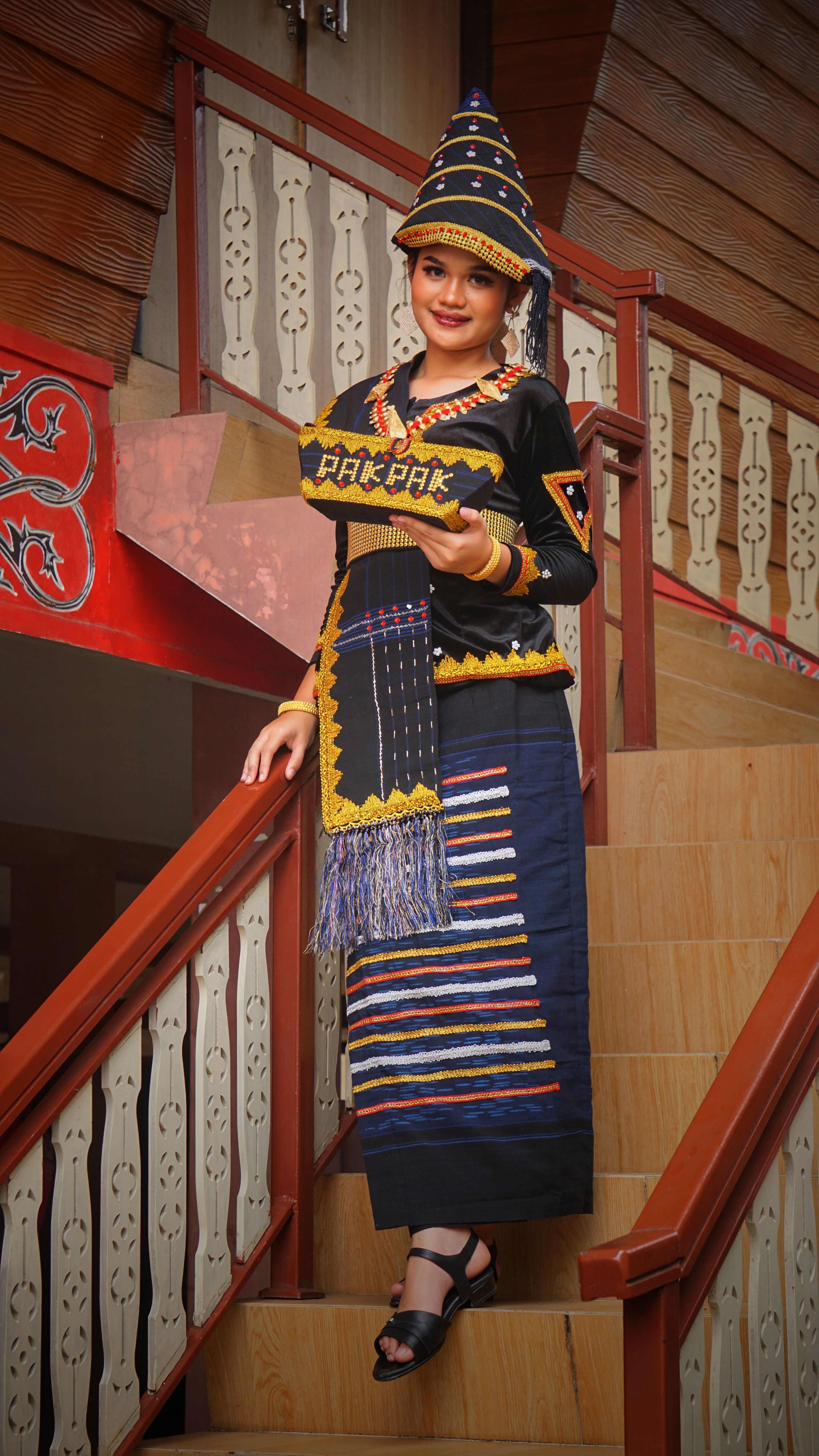 Woman in traditional Batak attire on staircase, Jakarta.