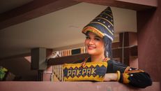 A woman in traditional Pakpak attire smiles indoors in Jakarta, Indonesia.