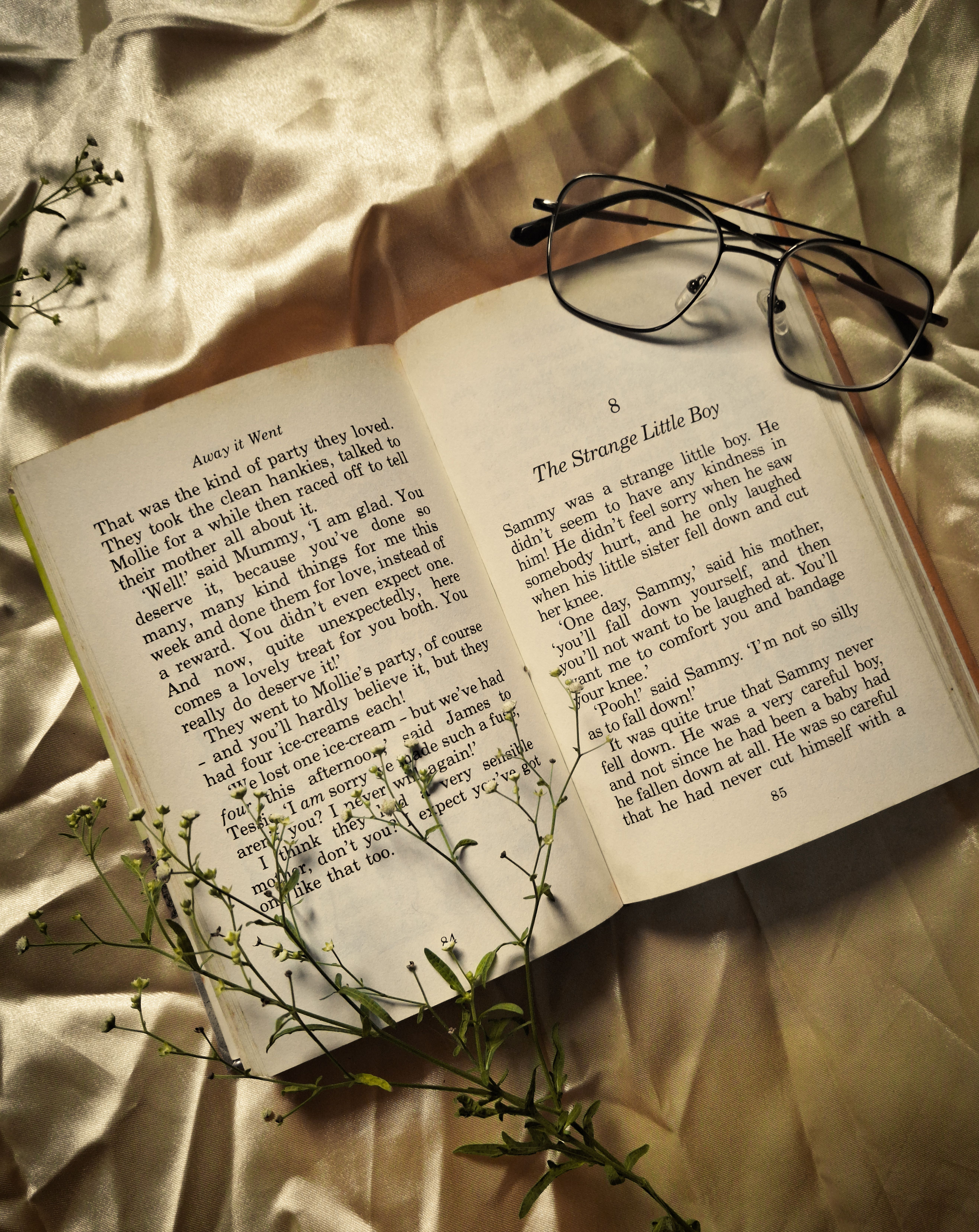 Open book with eyeglasses on silky fabric, evoking a vintage and intellectual mood.