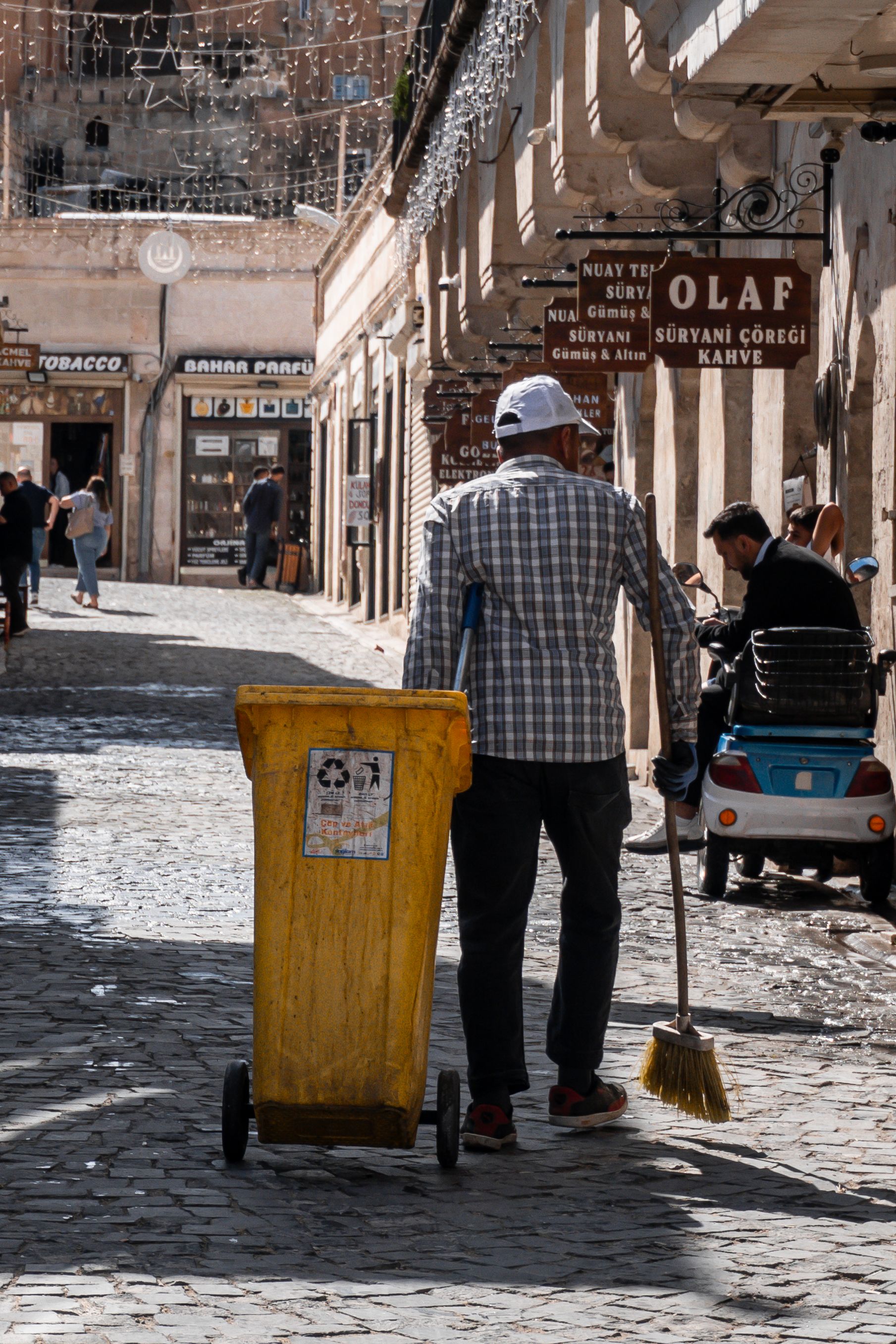 A street sweeper cleaning a cobblestone street in historic Mardin, Türkiye.