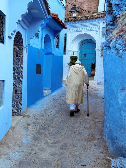Free Elderly man in traditional attire walking through Chefchaouen's iconic blue alleyways. Stock Photo