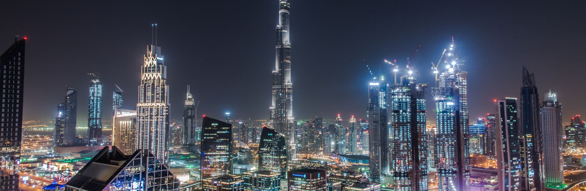 A stunning view of Dubai's illuminated skyline featuring the towering Burj Khalifa at night.