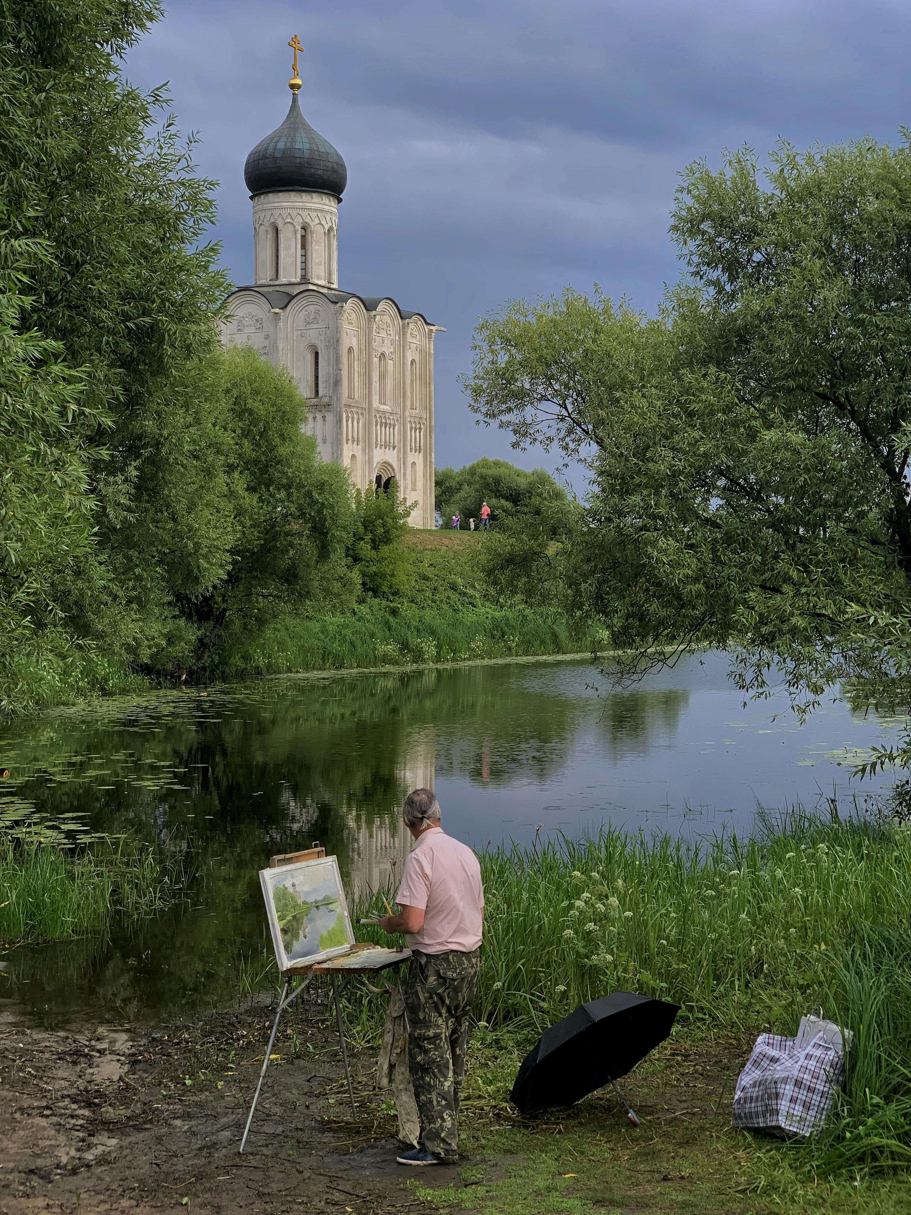 An artist paints outdoors near the historic Church of the Intercession on the Nerl River.