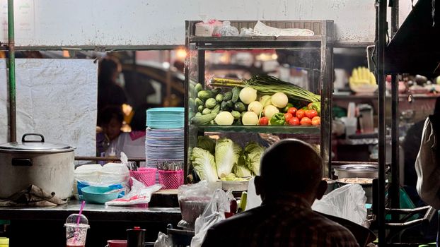 Explore the vibrant street food scene at a Chiang Mai night market with fresh vegetables on display.