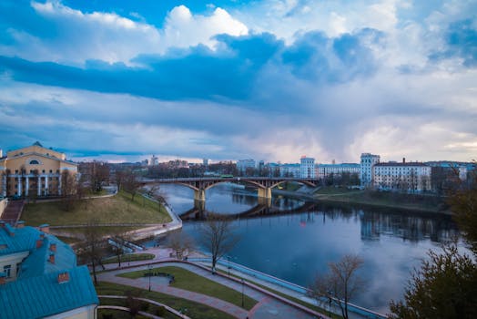 黄昏时分，在宁静的城市景观和多云的天空下，一座桥倒映在平静的河流上