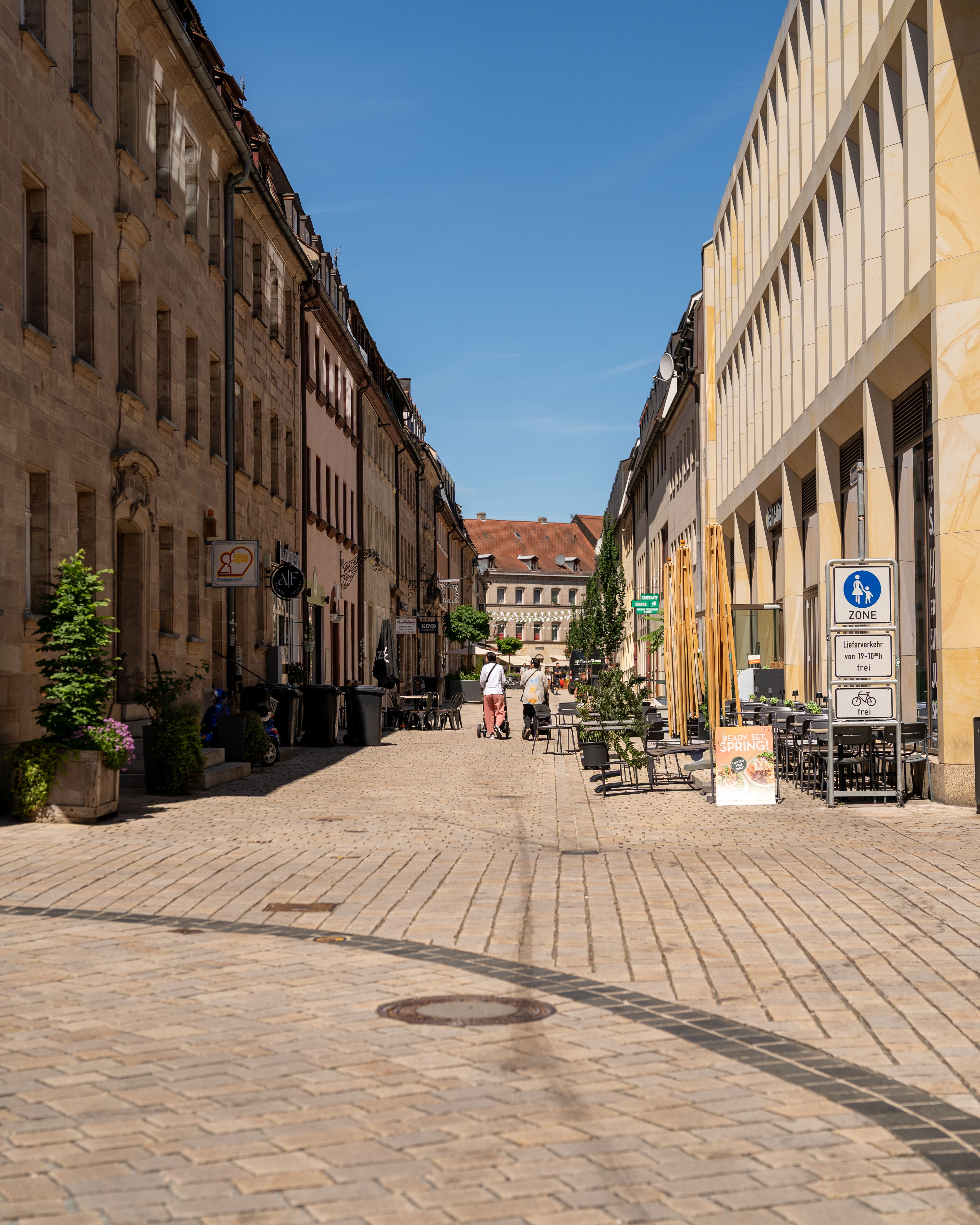 Explore the serene cobblestone streets of a historic European city on a sunny day, perfect for leisurely strolls and enjoying outdoor cafes.