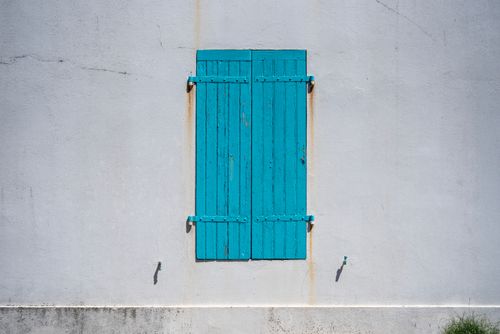 Free Simple and minimalist exterior shot of closed blue wooden shutters on a white wall. Stock Photo