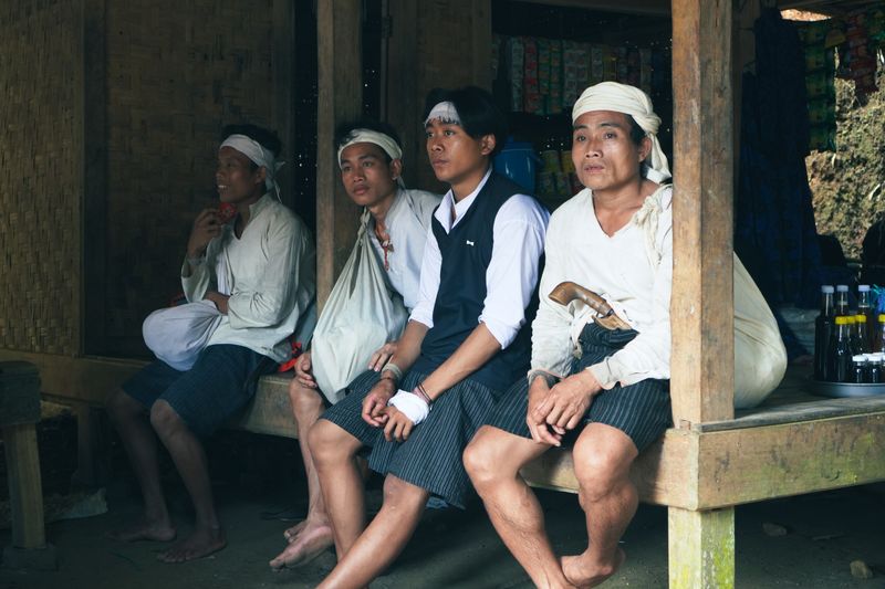 Group of adults in traditional Banten attire sitting in a wooden structure.