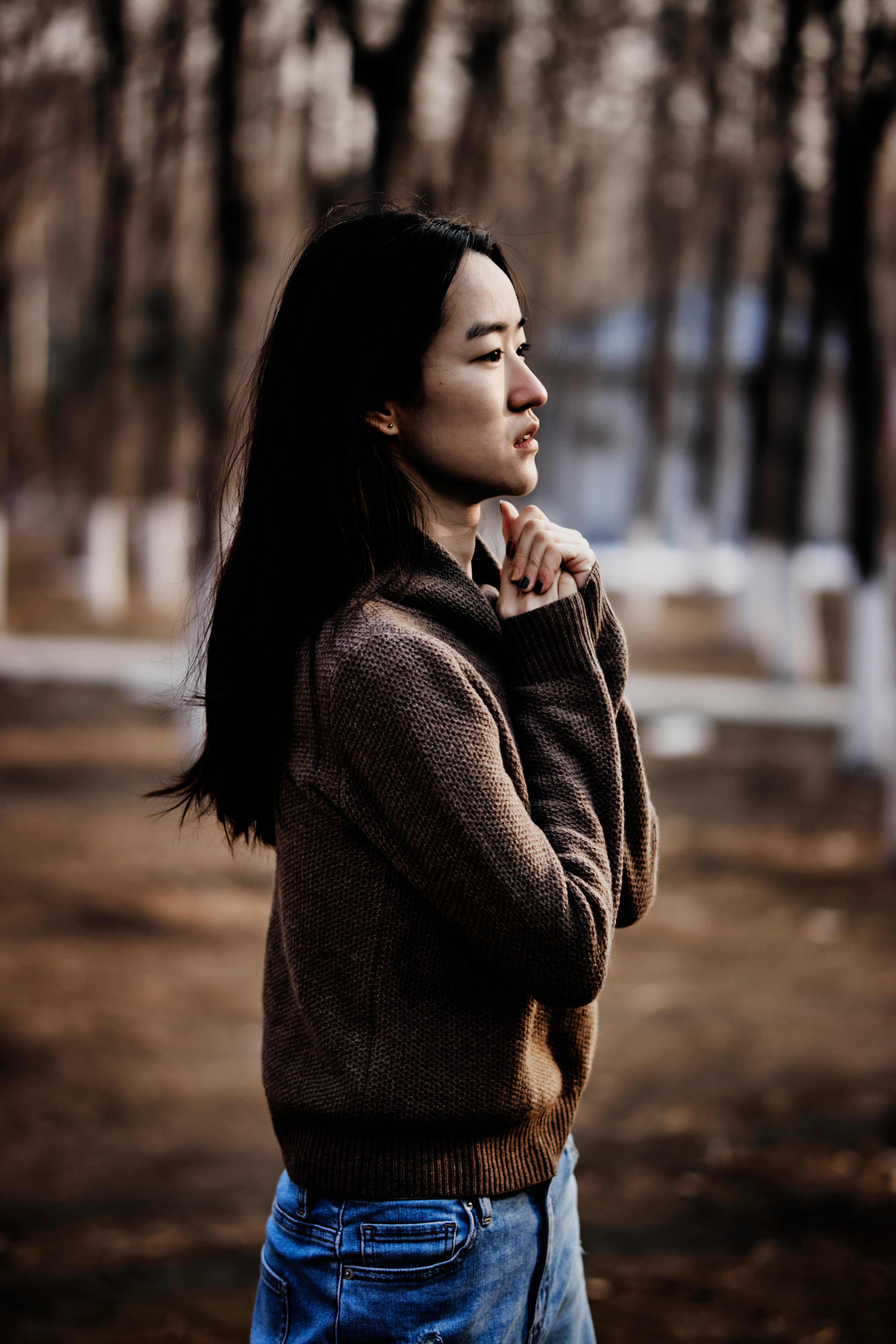 在凉爽的秋日里，一位体贴的女人穿着毛衣，站在森林中