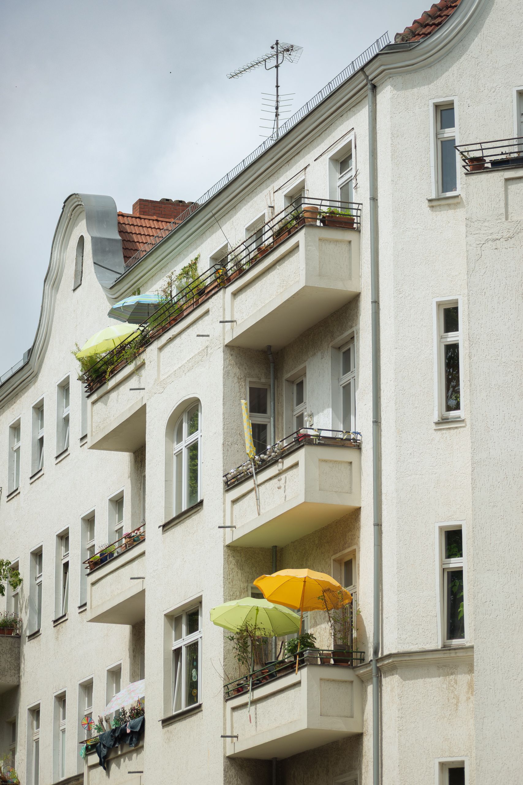 Free A classic city apartment building with sunny balconies and colorful umbrellas. Stock Photo