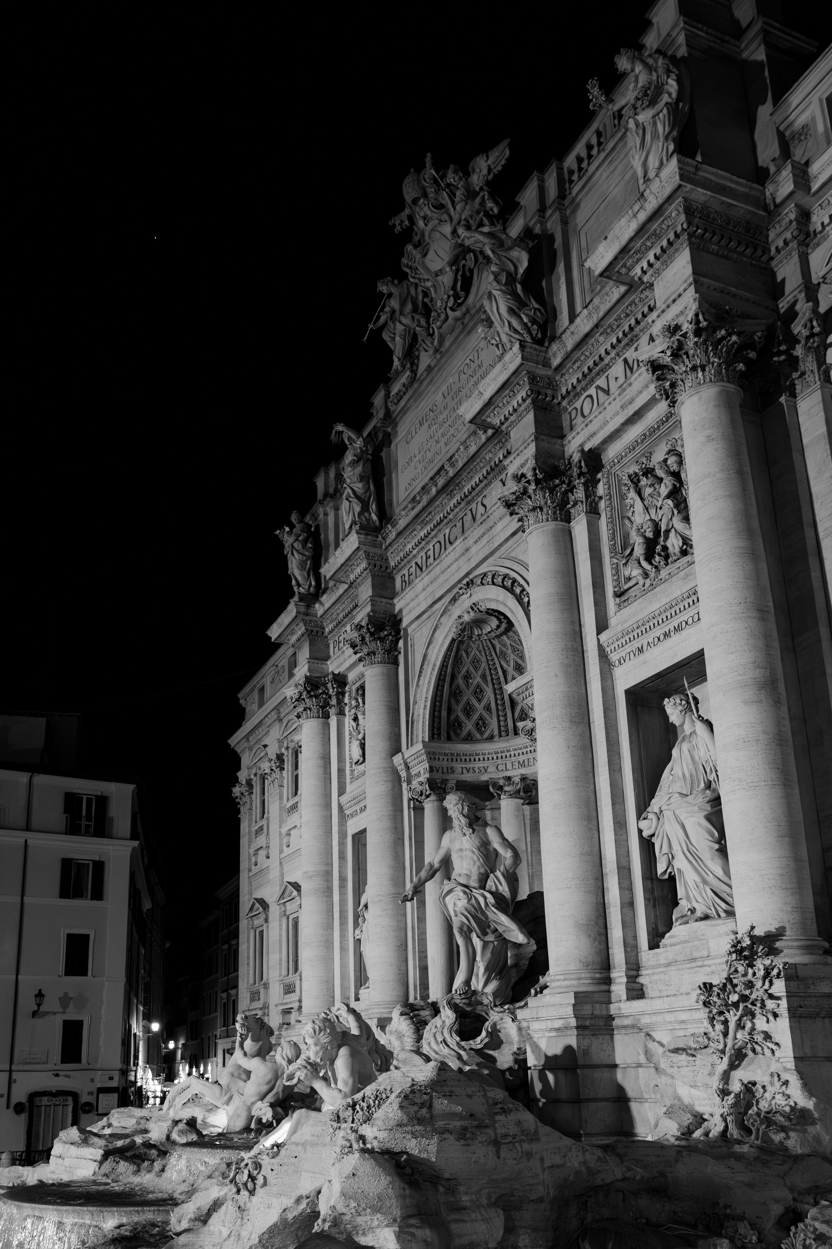 Stunning black and white night shot of Trevi Fountain, Rome capturing its iconic statues and architecture.