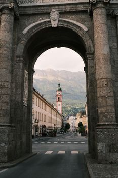 Scenic view through a historic archway in Innsbruck, Austria with mountains in the background.
