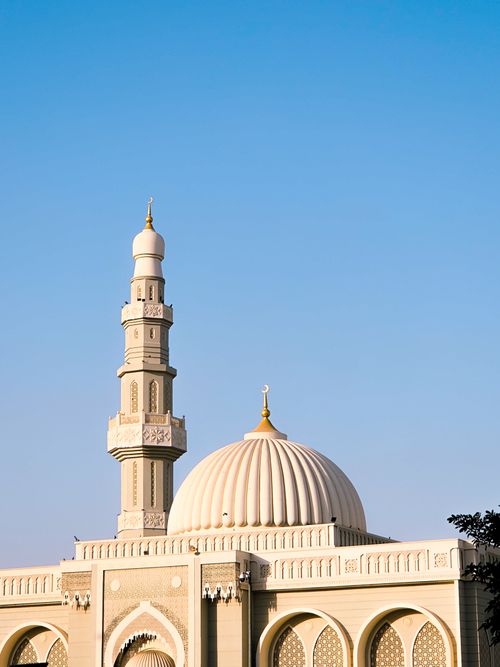 Free A beautifully designed mosque with a prominent dome and minaret against a clear blue sky in Sharjah, UAE. Stock Photo