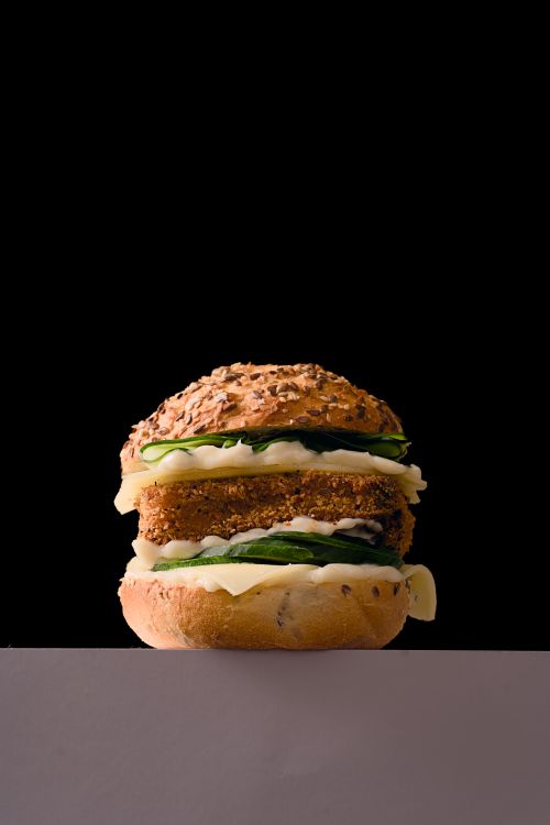 Free A delicious gourmet vegan burger with fresh veggies on a black background. Stock Photo