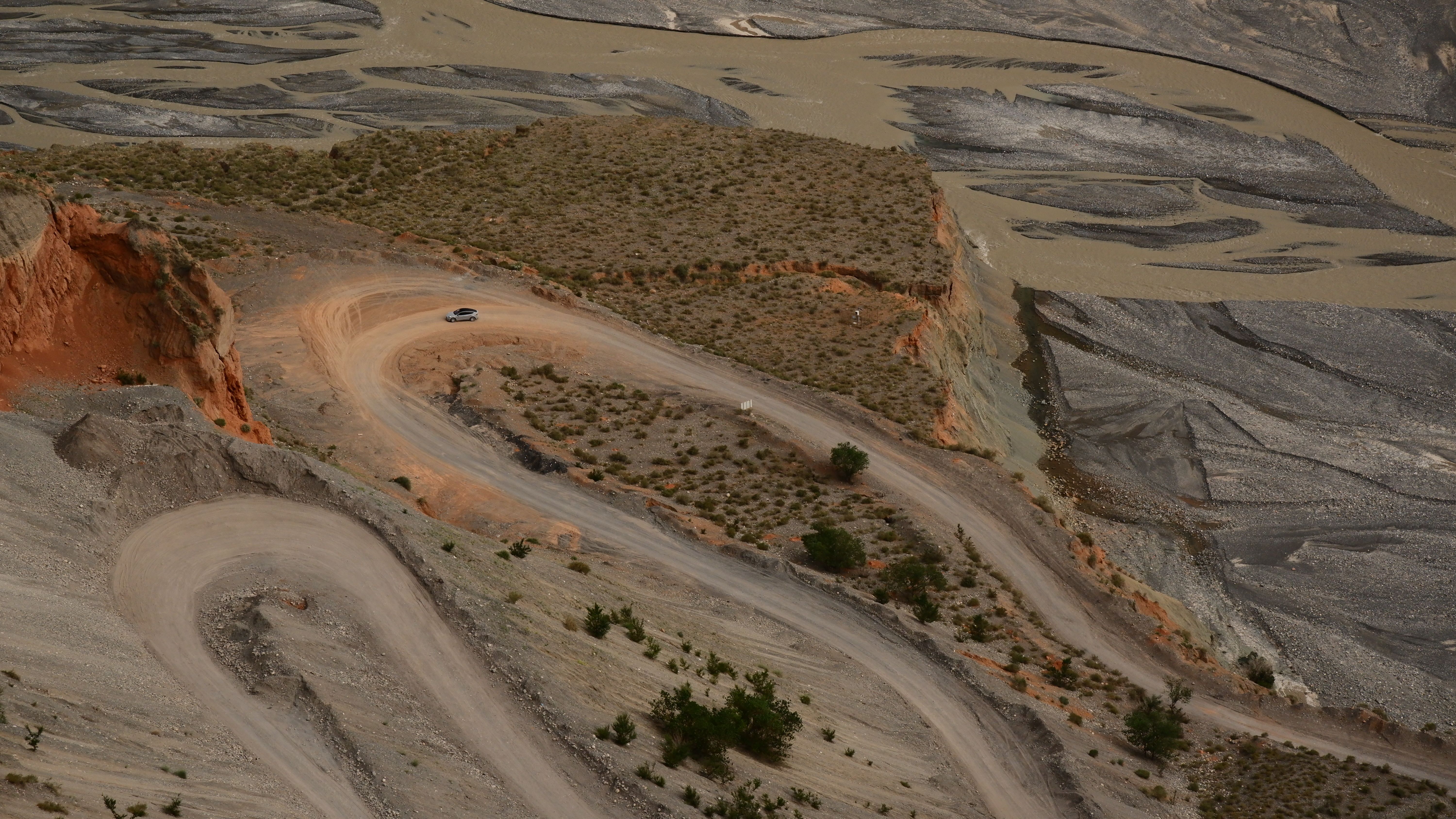 Aerial view of a winding road through Xinjiang's desert landscape with unique geological formations.